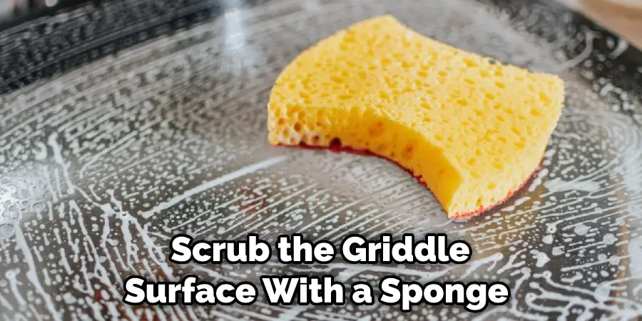 Scrub the Griddle Surface With a Sponge 