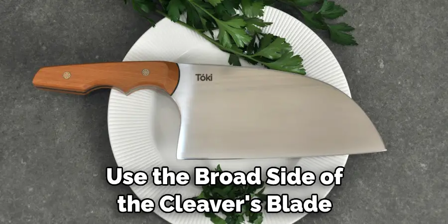 Use the broad side of the cleaver's blade